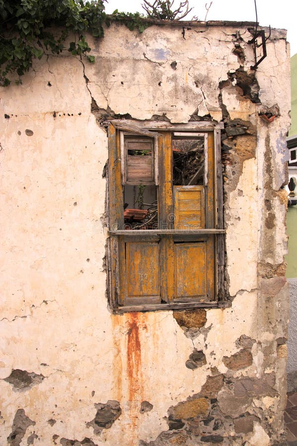 Window in an abandoned house with copy space. Street-facing window showing dilapidated condition of an old house that no one is trying to repair with copy space stock photo