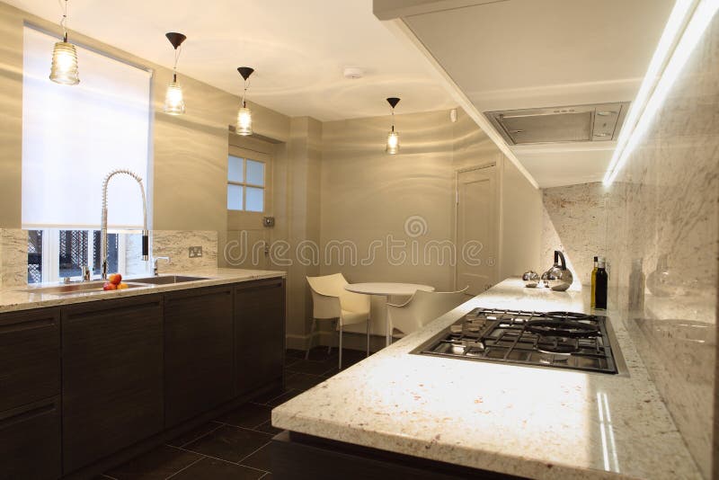 Stylish fitted kitchen with marble counter tops. Stylish fitted kitchen interior with marble counter tops and fancy lighting stock image