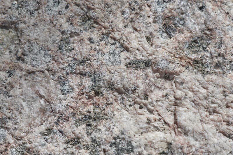 The surface of the chipped granite stone, rough, unpolished with multicolored splashes, natural, not treated,  as a background for. Design work. Slightly stock photo