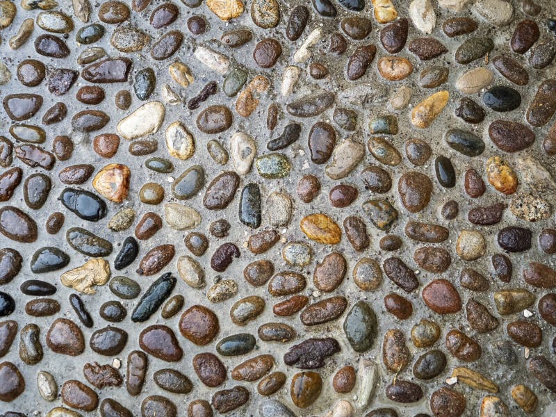 The surface of the sidewalk is beautifully paved with colorful pebbles. The sidewalk glistens with water. Colorful stone background stock images