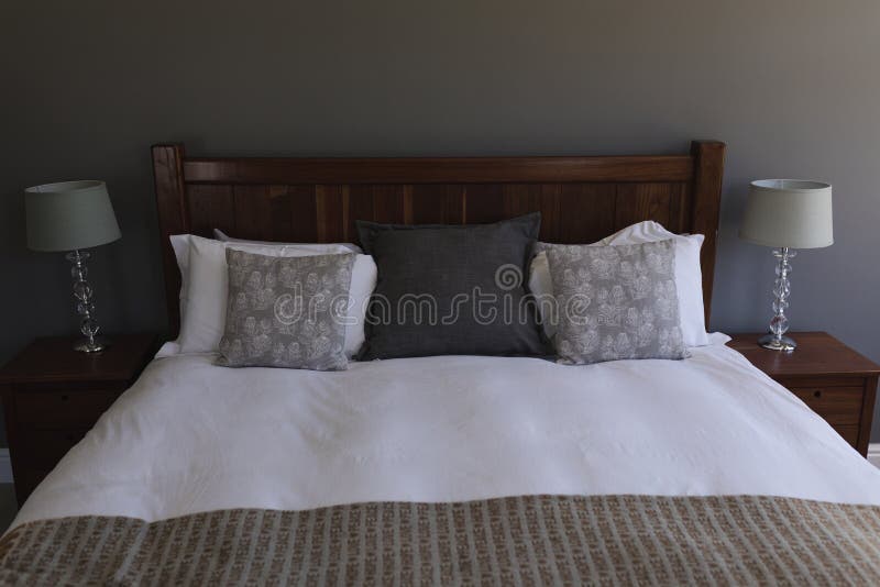 Table lamp and pillows arranged on a bed in bedroom stock photos