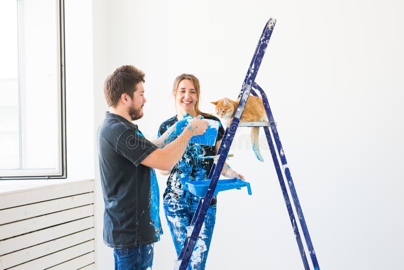 Teamwork and repair concept - young couple with cat doing a renovation in new apartment royalty free stock photography