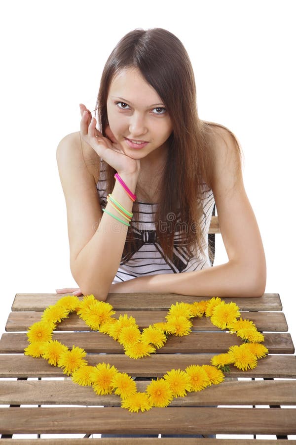 Teen girl 15 years old, made of yellow flowers valentine. One girl brunette teen Caucasian, 15 years old, sitting at a table on which is lined with heart stock image