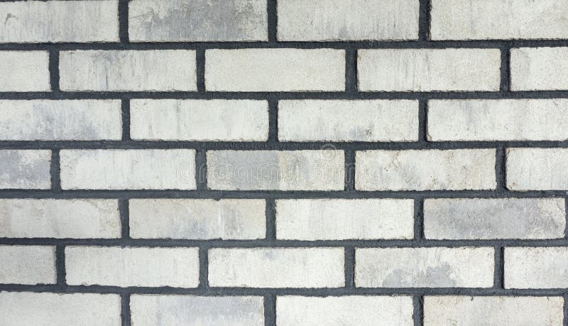 The texture of the facing bricks is white with a rough black grout for mocap. Photo of a wall lined with white bricks in the loft. Stylish texture of the facing stock photos