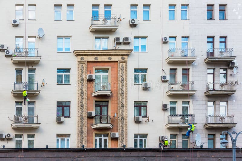 Three plasterer-painter repairing the facade of the house. Three plasters perform repair of the facade of the building at a height of royalty free stock photo