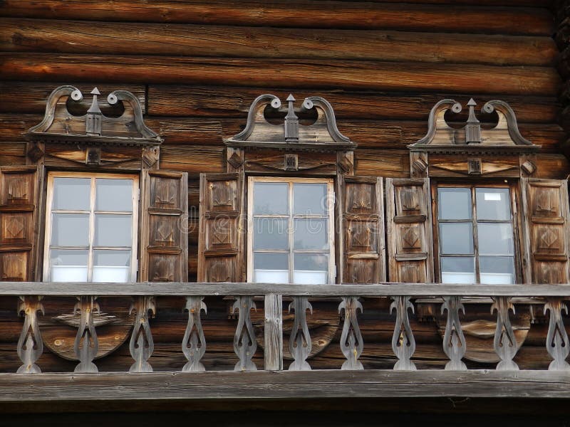 Three windows with carved platbands on wooden house stock images