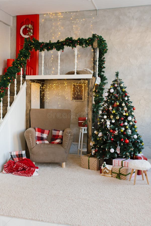 Traditional classic Christmas tree and beige armchair, stairs to the second floor in the living room or dining room. In the house stock photo