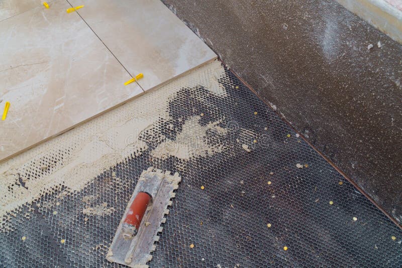 Troweling mortar a concrete floor in preparation for laying floor tile. Troweling mortar a concrete floor in preparation for laying floor ceramic tiles stock image