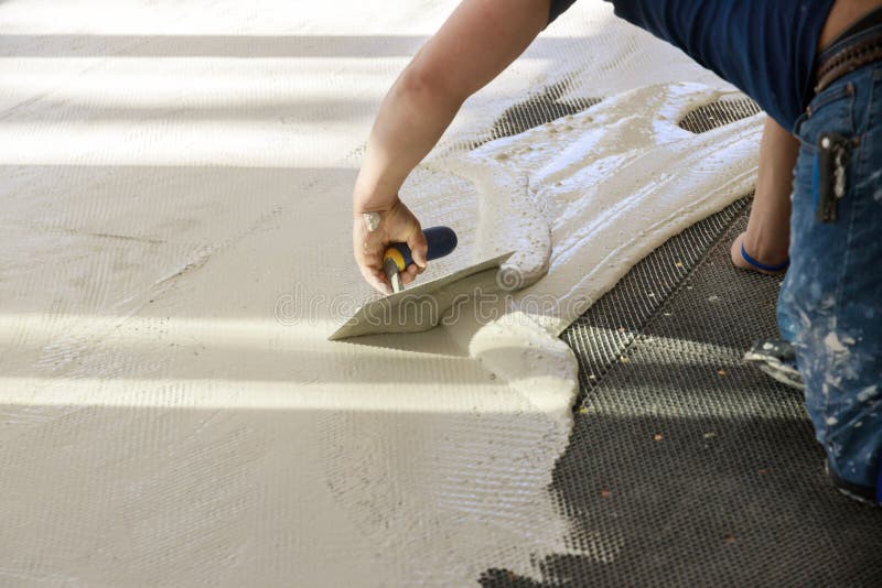 Troweling mortar concrete in preparation for laying for tiler on the floor. Professional worker troweling mortar concrete in preparation for laying for tiler on royalty free stock images