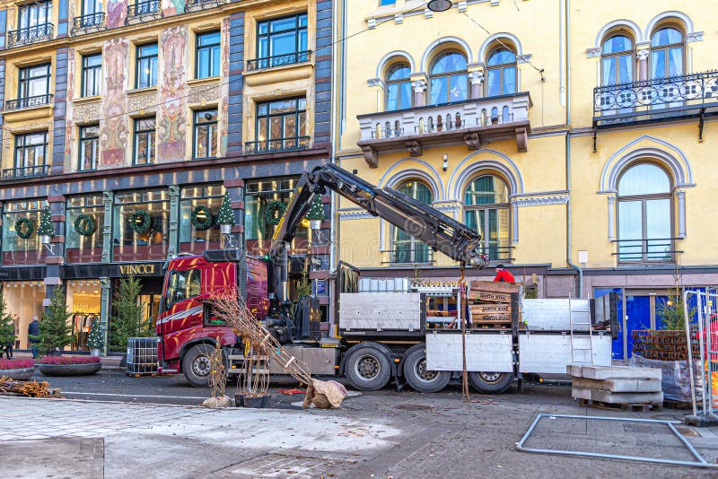 A truck driver unloads building materials to the ground using a built-in crane royalty free stock photo