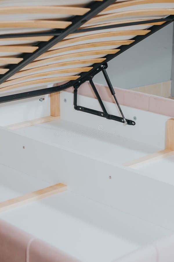 Vertical shot of a bed with wooden frame and lifting mechanism for the storage stock photo