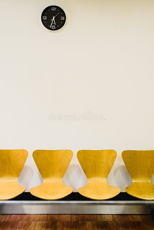 Waiting room with empty wooden chairs and wall clock, waiting concept royalty free stock photography