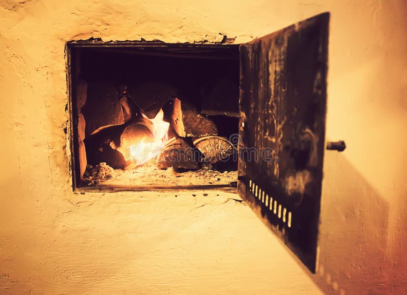 Warm light of a burning fire in a fireplace in old Russian stove. Flame and firewood background. Detail of interior. Warm light of a burning bright fire in a royalty free stock image