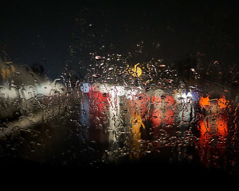 Waterdrops on the window blurring the lights outside with a black background royalty free stock images