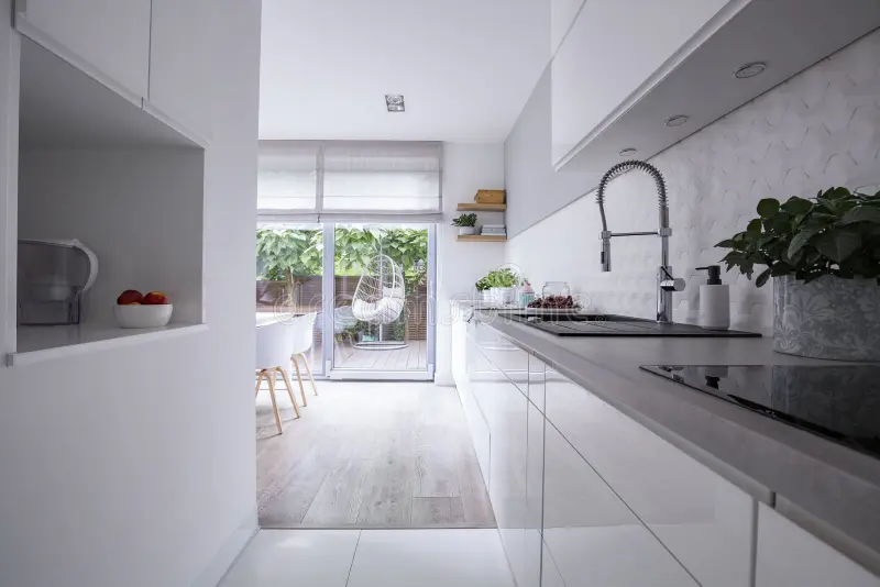 White cabinets in bright modern kitchen interior of house with terrace. Real photo royalty free stock images