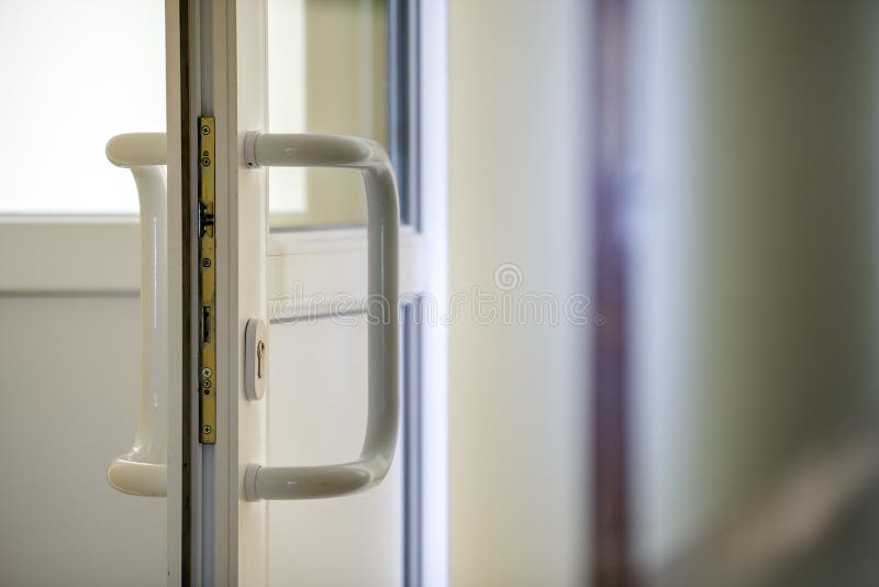 White plastic door detail with metal lock, handle and transparent glass on blurred interior background. Installation and design. Concept royalty free stock photo