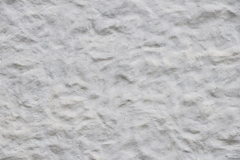 White wall of embossed decorative plaster. Rough white wall surface of decorative embossed painted lime plaster texture background royalty free stock photography