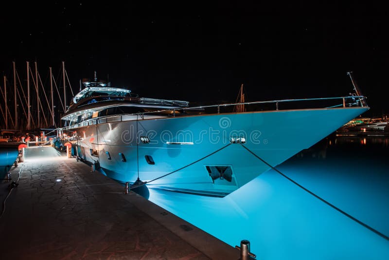 White yacht with a luminous bottom is in the marina at night. Big white yacht with a luminous bottom is in the marina at night, luminous water royalty free stock photos