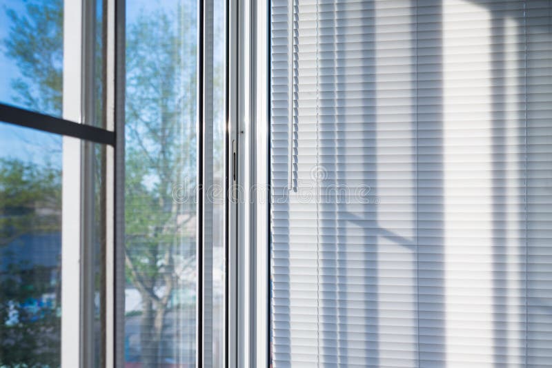 Window blinds. Closed plastic blinds on the window with the reflection in the glass stock image