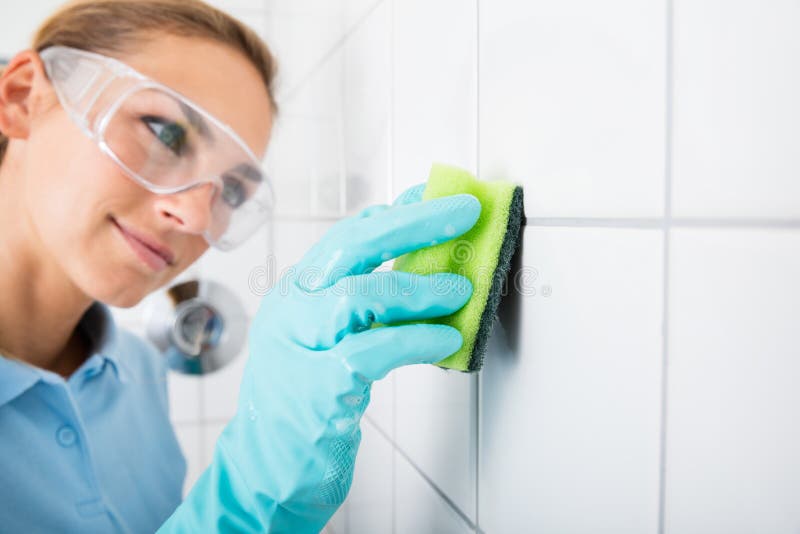 Woman Cleaning The White Tile Of The Wall royalty free stock photo