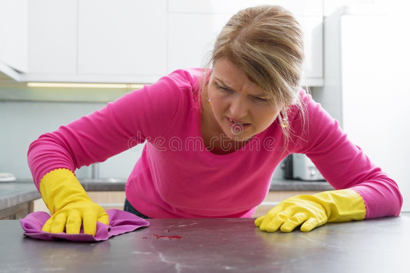 Woman clening a stain on kitchen counter. Housewife clening a stain on kitchen counter royalty free stock photos