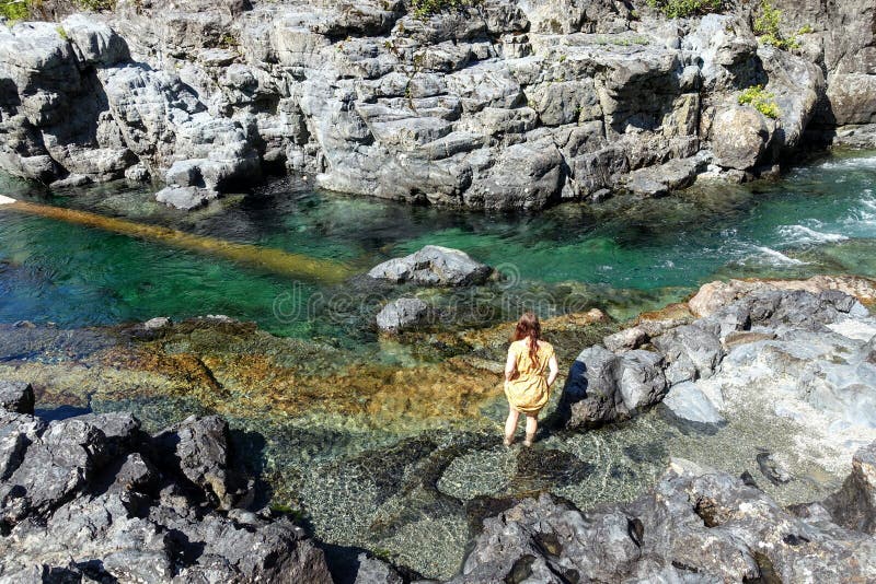 A woman exploring Wally Creek, on the way to Tofino.  The water is magical for swimming, the flowing creek water glistens. With a clear, aquamarine hue that is royalty free stock photos