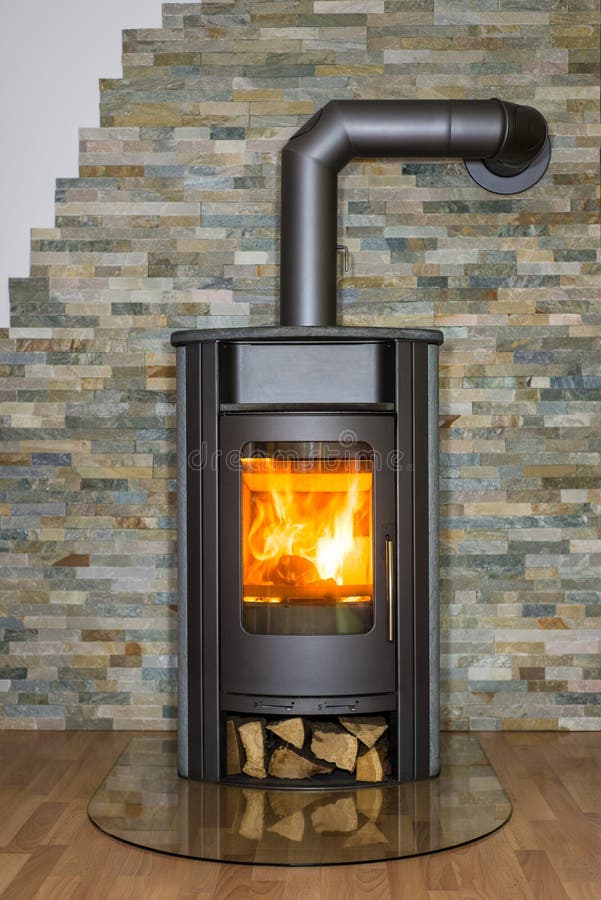 Wood burning stove in house. Roaring fire inside wood burning stove in living room royalty free stock photography