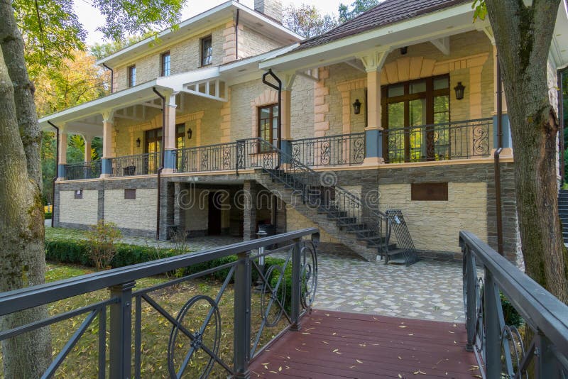 Wooden bridge with metal railings leading to a beautiful house with a staircase to the second floor stock photo