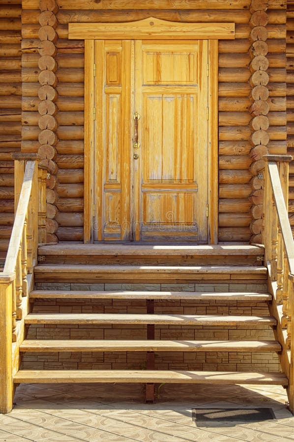 Wooden porch, door and staircase in a log frame house. The ancient technology of building a Russian log hut and churches.  stock photos