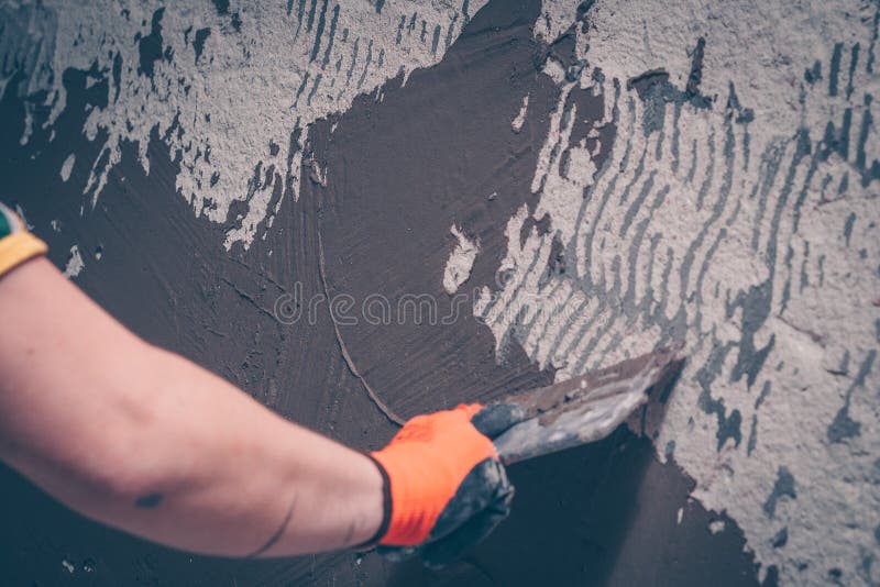 The worker aligns the wall with a tile adhesive applying it with a spatula. Preparation for tiling royalty free stock image