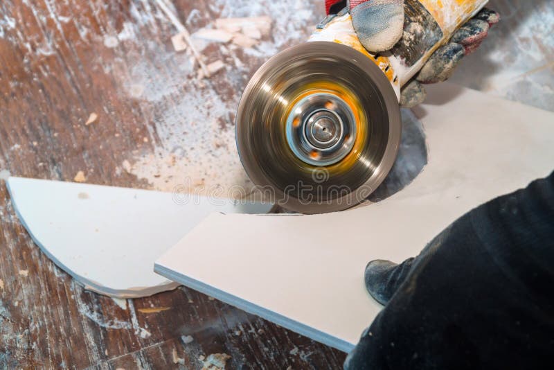 Worker cutting tile using grinder cut into layers of ceramic floor tiles. Worker cutting a tile using grinder cut into layers of ceramic floor tiles flooring stock photography