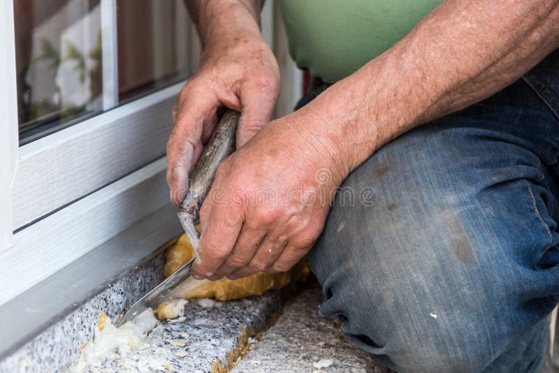 Dirty worker hands - craftsman removes assembly foam with a spatula, close up royalty free stock photography