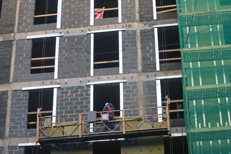 A worker installs heat insulation on the wall of a new building. stock images