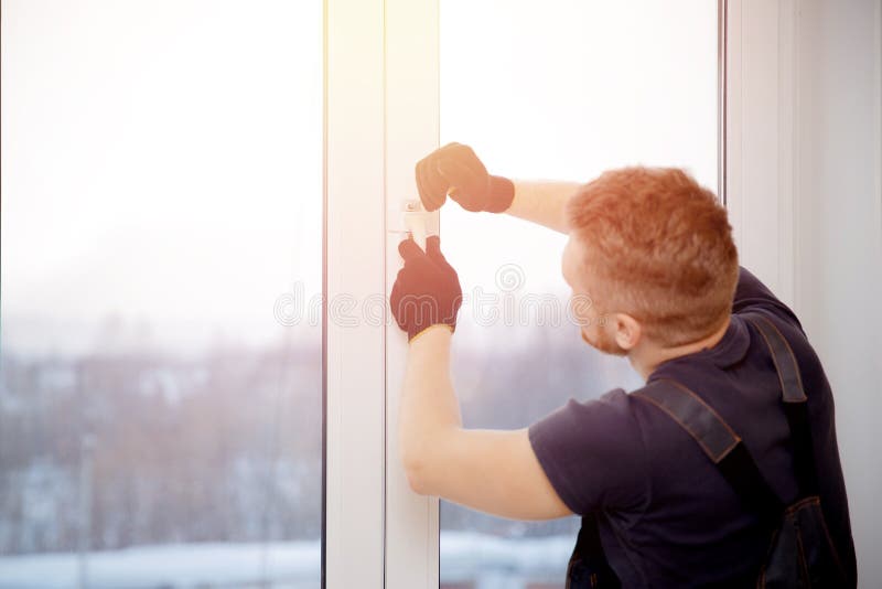 Worker man installs plastic windows and doors with double-glazed white stock photography