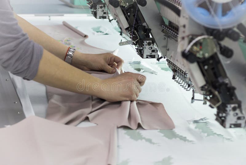 The worker removes the finished embroidery from the embroidery frame on the embroidery machine stock photo