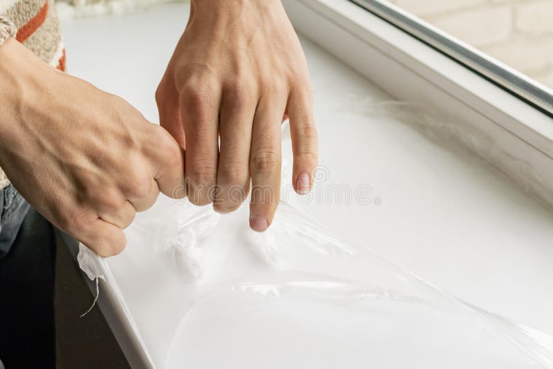 A worker removes plastic film from the window sill stock photography