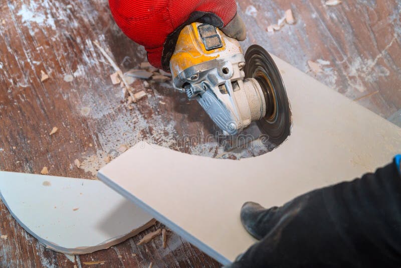 Worker using an grinder cutting a floor tile. Worker hand cutting ceramic floor paving tile with electric angle grinder flooring construction material tool tiler royalty free stock images