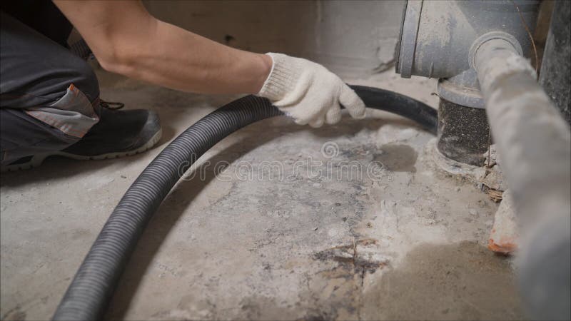 A worker vacuums a concrete floor. Construction services for cleaning the sleeve with an anchor bolt. dust removal with a vacuum. Construction services for royalty free stock photos