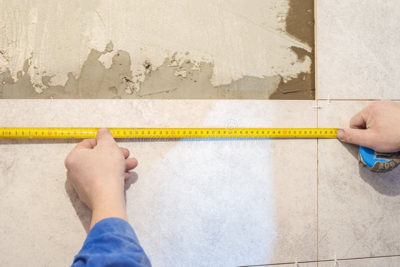 Workers hands and measuring tape. Construction repair work in the room for laying ceramic tiles stock photo