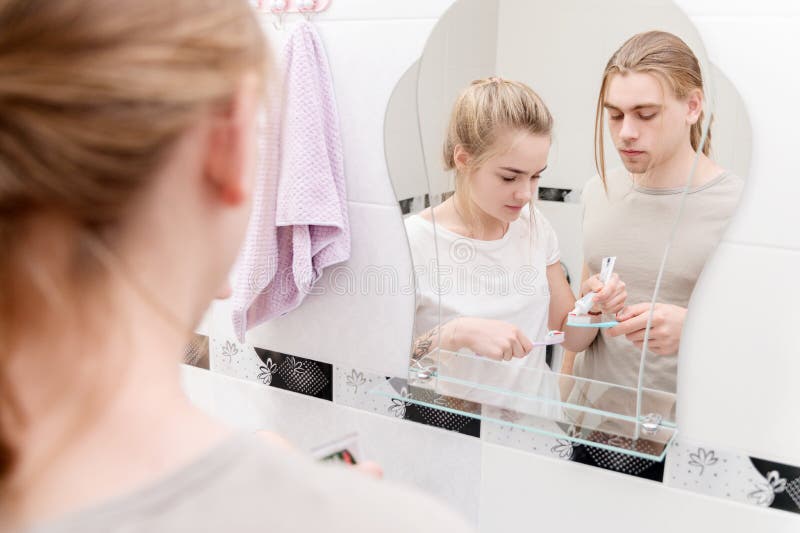 A young married couple of long-haired hipsters in the bathroom getting ready for a joint brushing and morning bath. Routines. Put toothpaste on the toothbrushes royalty free stock photos