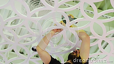 Worker installs beautiful white decoration under ceiling. KAZAN, TATARSTAN/RUSSIA - FEBRUARY 09 2020: Young bearded worker installs beautiful white decoration stock footage